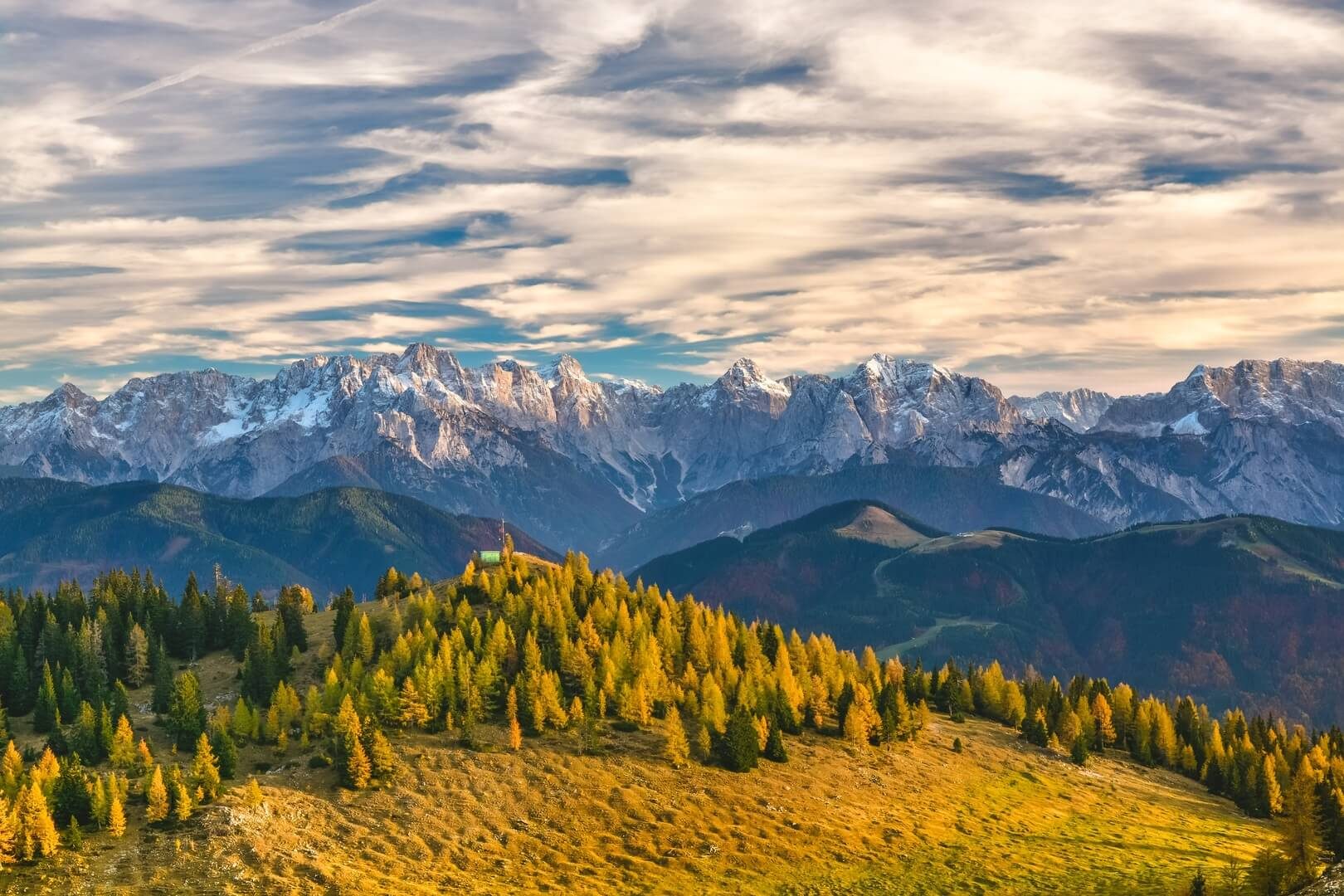Sunlit forest and mountain ridges beneath a cloud-filled sky